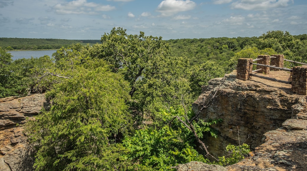 Fenced Off Viewpoint Overlooking Blue Lake Surrounded by Forest of Green Trees With Rocky Landscape in Lake Mineral Wells State Park in Mineral Wells, Texas