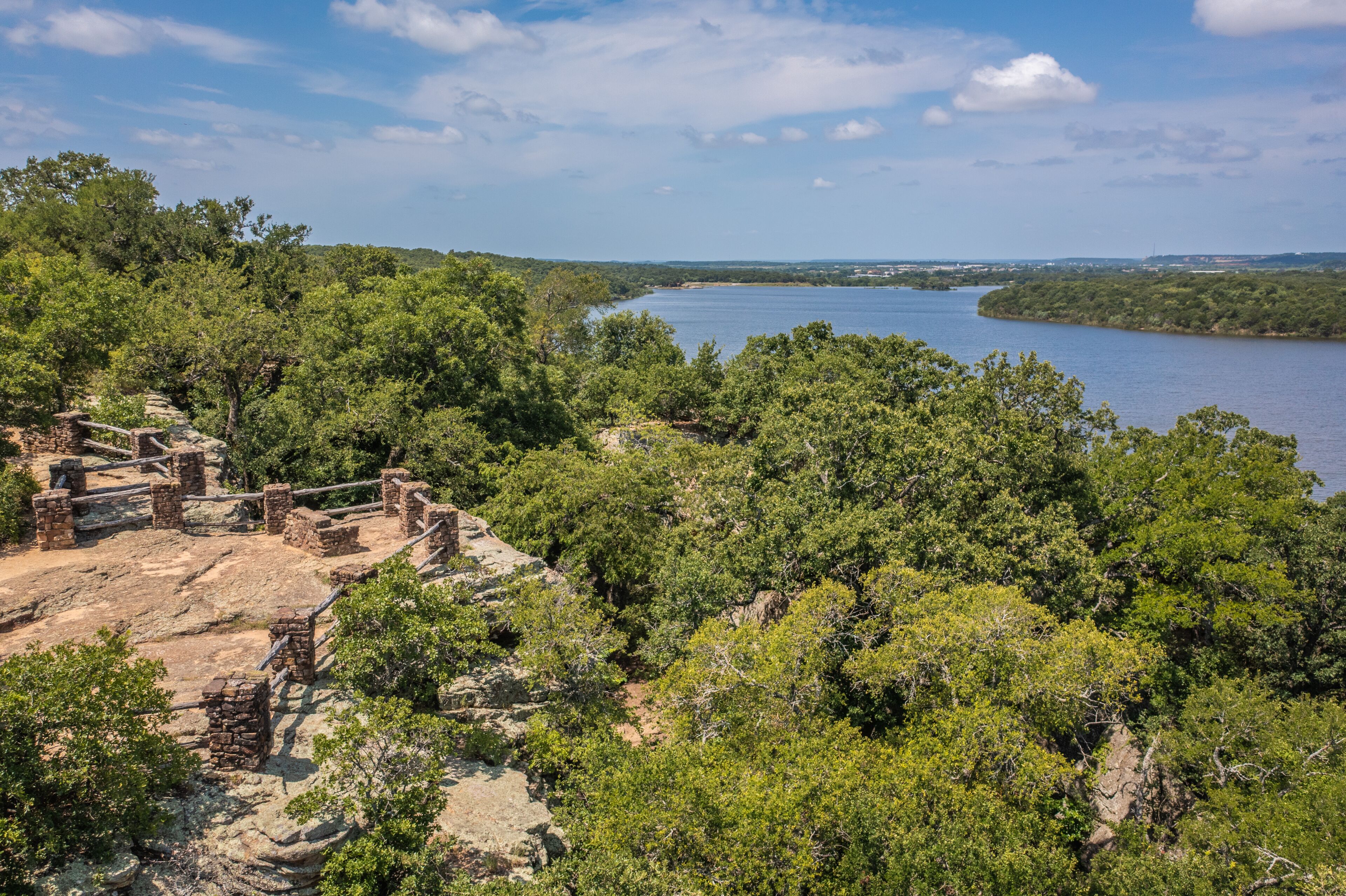 A historical site with ruins and a lake surrounded by dense greenery.
