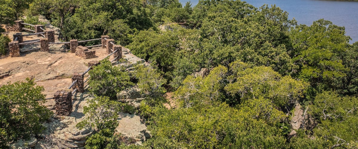 A historical site with ruins and a lake surrounded by dense greenery.