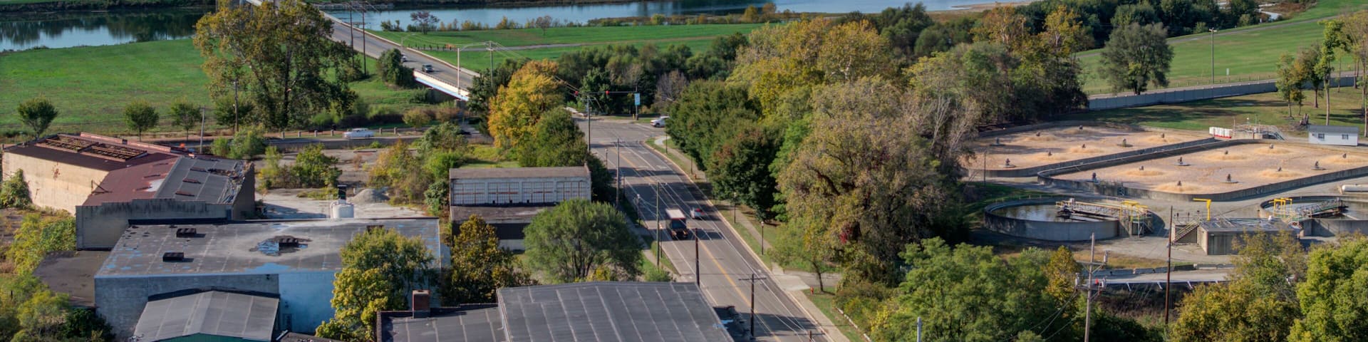 Aerial view of a winding river reflecting the sky, a bridge connecting lush green banks, and a road leading through Middletown's industrial edge, Middletown, Ohio, United States.