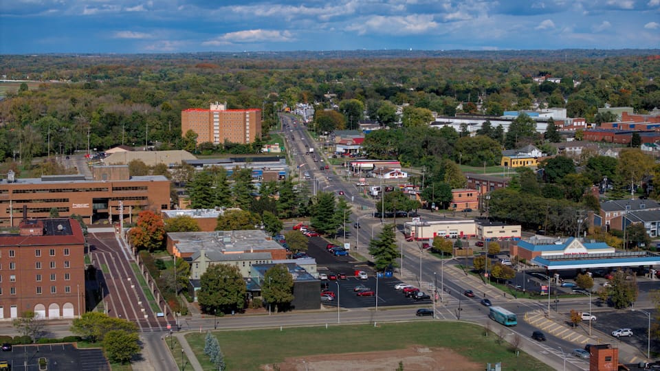 A cityscape with a prominent red building, a main road, and surrounding greenery.