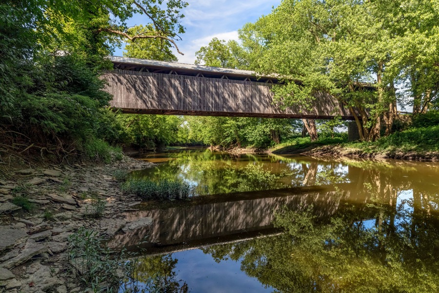 Displaying a beautiful reflection in the East Fork of the Little Miami River, historic McCafferty Road Covered Bridge was built in 1877 in rural Brown County, Ohio.