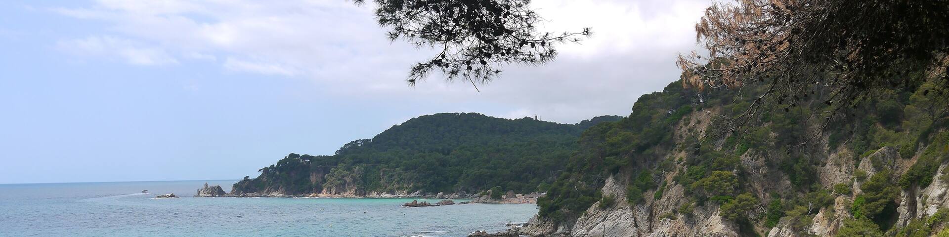 A coastal landscape with turquoise waters, rocky cliffs, and a sandy beach.