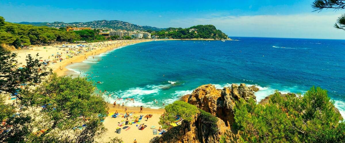 A crowd of vacationers enjoy the warm beaches of Costa Brava in Lloret de Mar. Panorama of Lloret de Mar.
