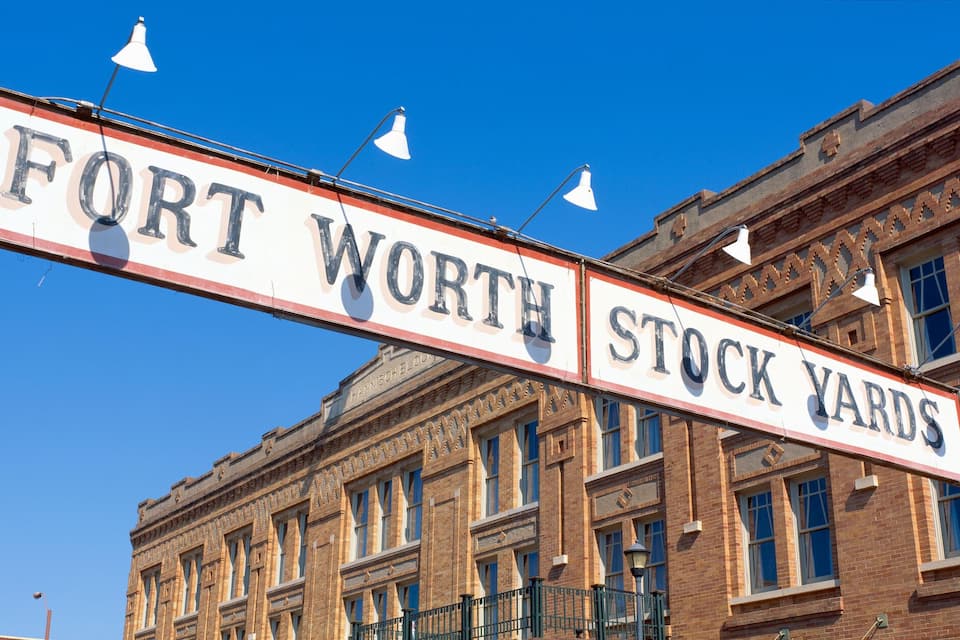 En gatukylt med texten ”FORT WORTH STOCK YARDS” mot en klar, blå himmel.