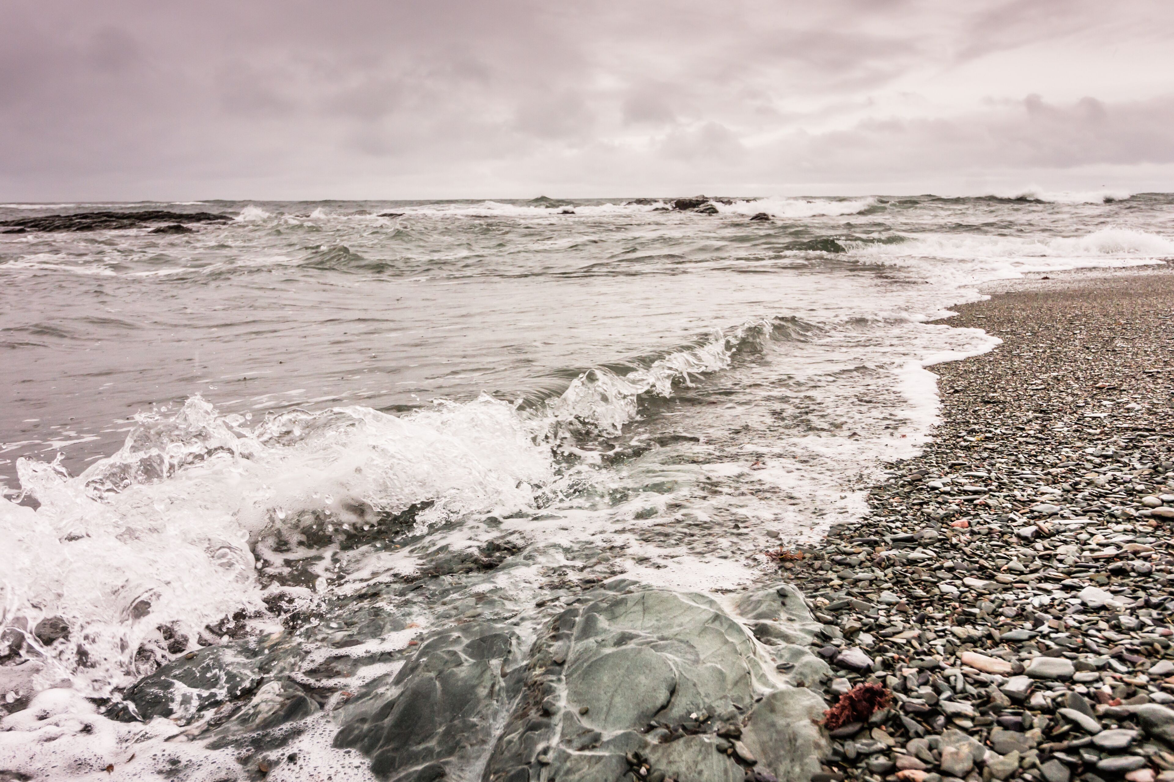 Waves break against the rocky coastline in Newport, Rhode Island, under a stormy sky