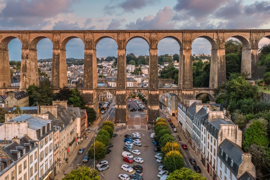 Un antico ponte in pietra con più archi che sovrasta un fiume, circondato da edifici urbani e vegetazione.