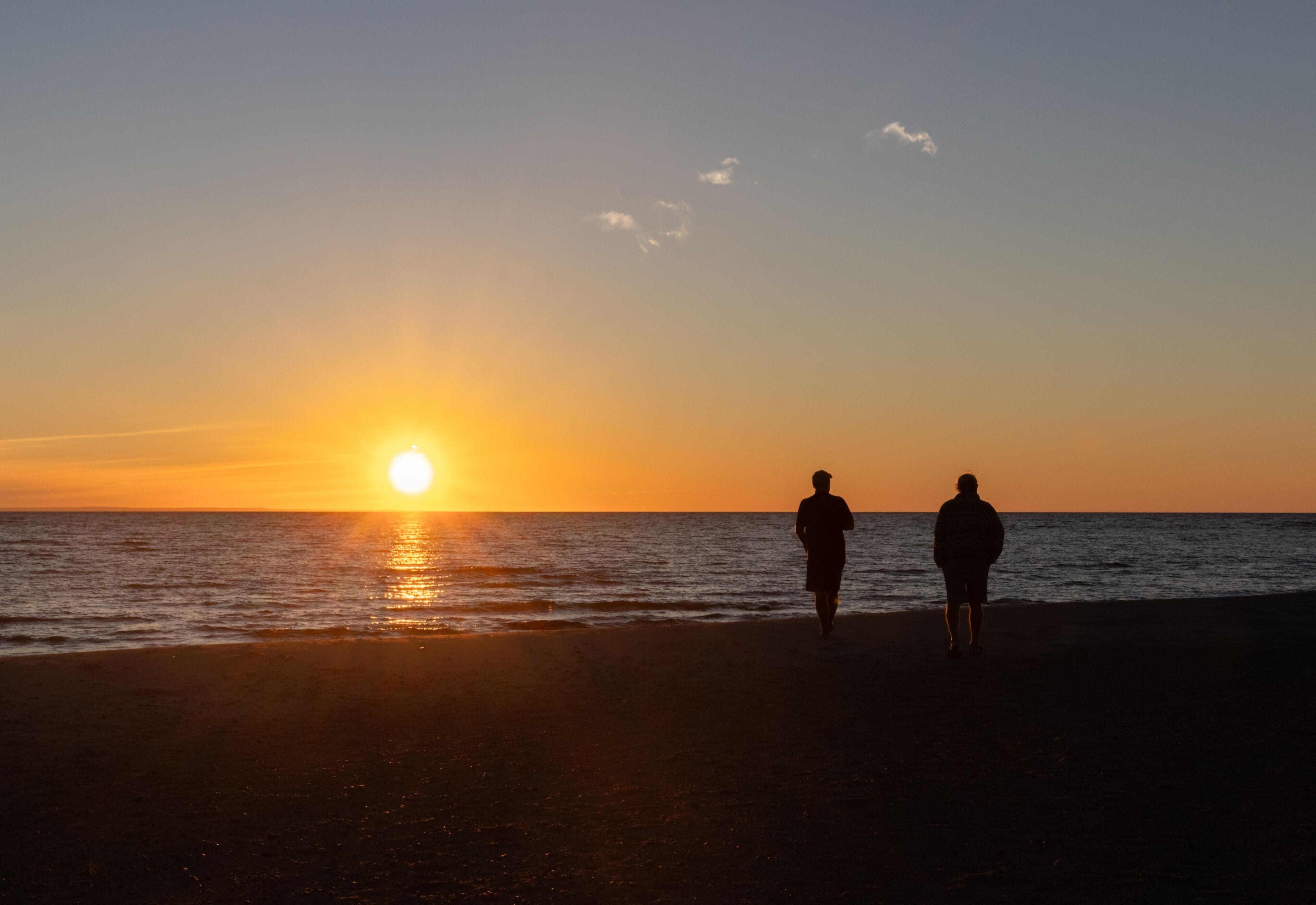 Two male friends watching the Georgian Bay sunset from the beach on a late summer evening near Lafontaine Ontario