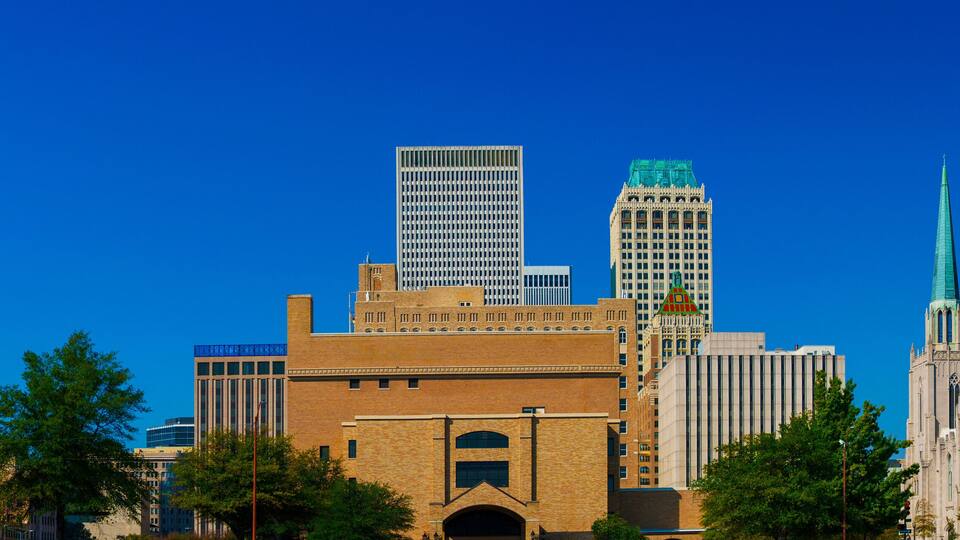 A city skyline with modern skyscrapers, historic buildings, and a prominent church spire.