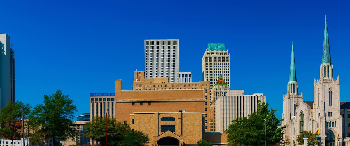 A city skyline with modern skyscrapers, historic buildings, and a prominent church spire.
