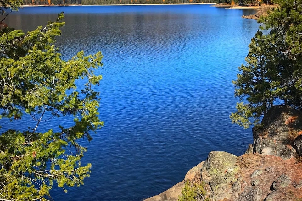 A lake surrounded by forested hills and rocky terrain.