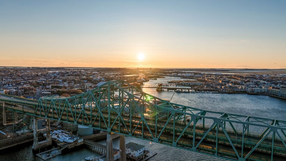 A green bridge over a river with a sunset in the background.