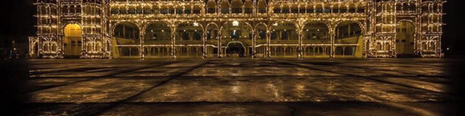 A grand illuminated building with intricate architecture and a large open courtyard.