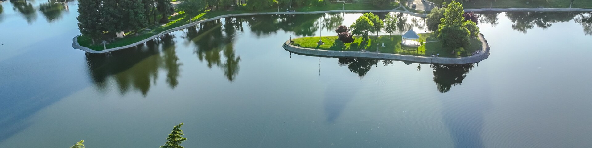 Um lago com ilhas, cercado por vegetação densa e edifícios residenciais.