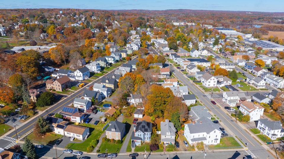 A suburban neighborhood with houses, streets, and autumn foliage.