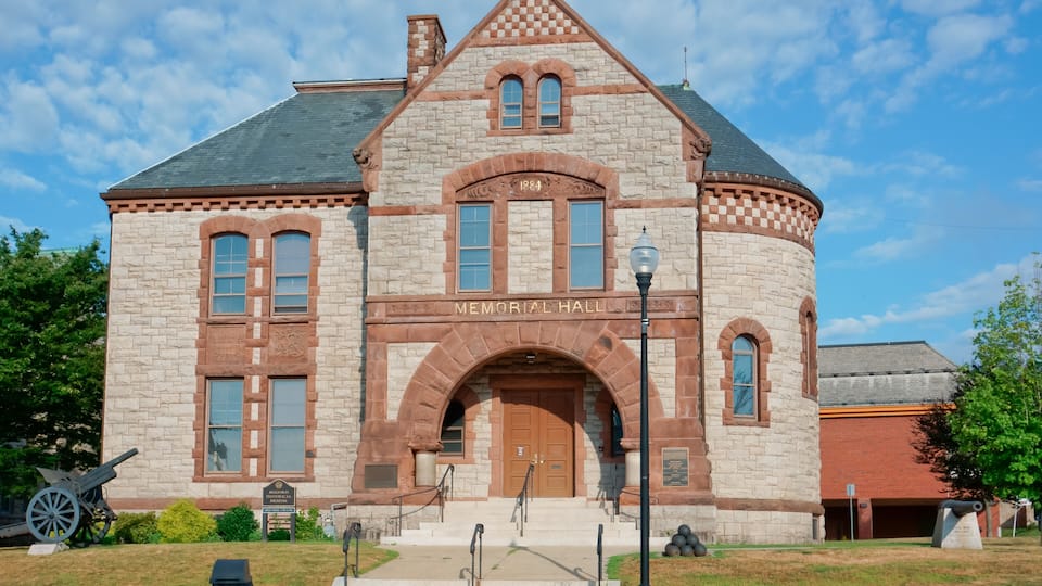 A stone building with a large arched entrance labeled "Memorial Hall" and a turret with a clock.