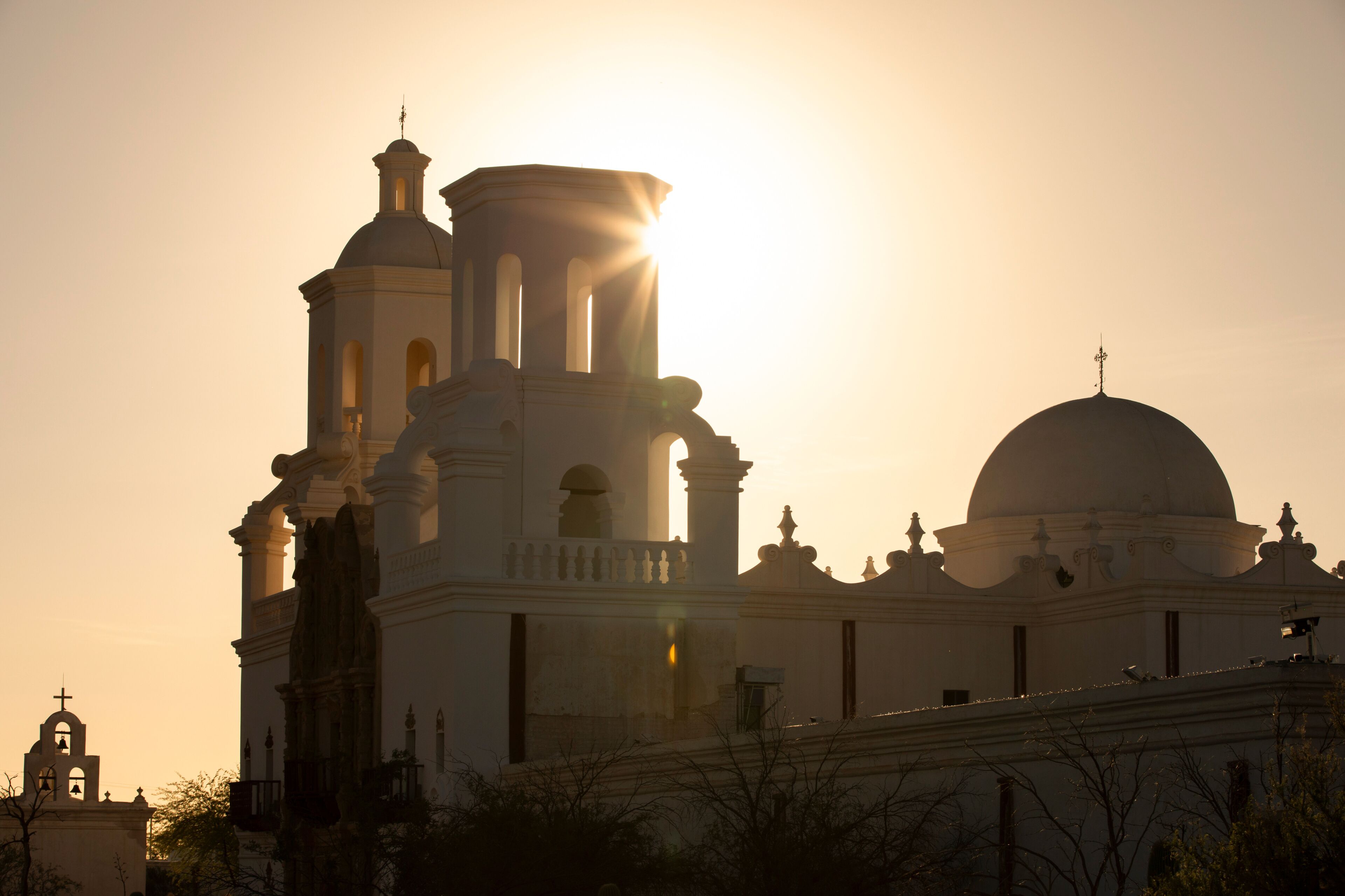 Una iglesia con campanario y cúpula, silueteada contra un atardecer.