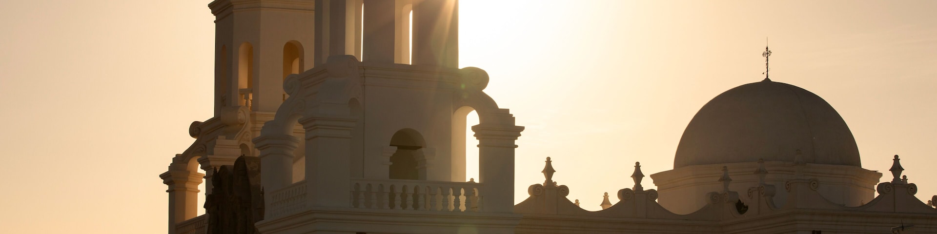 Una iglesia con campanario y cúpula, silueteada contra un atardecer.