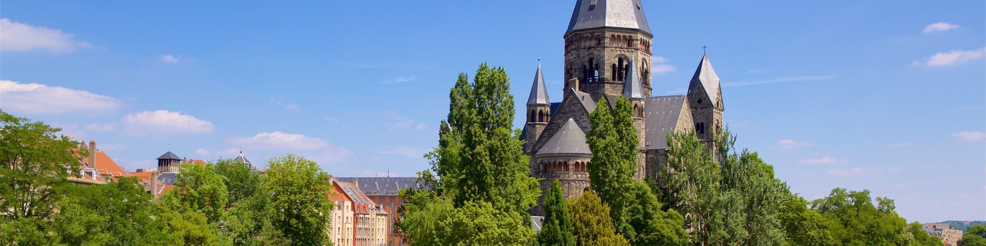 A historic church with a tall spire, a river, and a bridge.