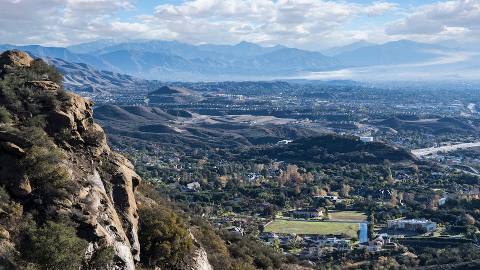 A mountainous landscape with a valley city, a river, and distant mountains.