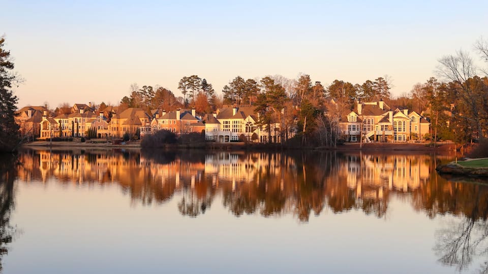 A lakeside residential area with multiple large houses reflecting on the water.