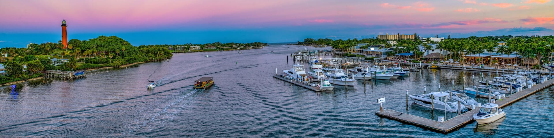 A marina with boats, a lighthouse, and a sunset sky.
