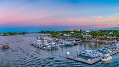 A marina with boats, a lighthouse, and a sunset sky.