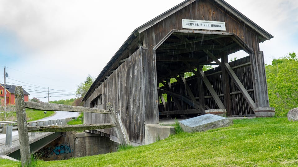 A rustic covered bridge named 'Brown's River Bridge' with a wooden structure and a signboard.