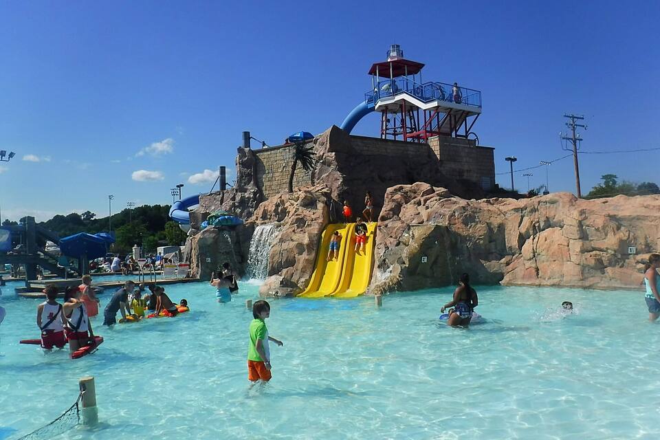 A water park with a large pool, a yellow slide, and a lookout tower.