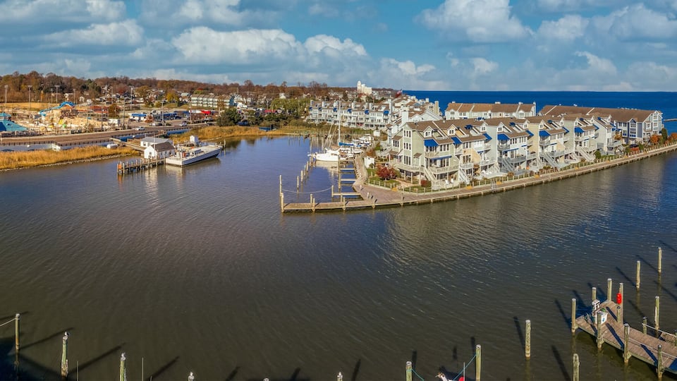 A harbor with boats docked, a pier, and a row of houses along the water.
