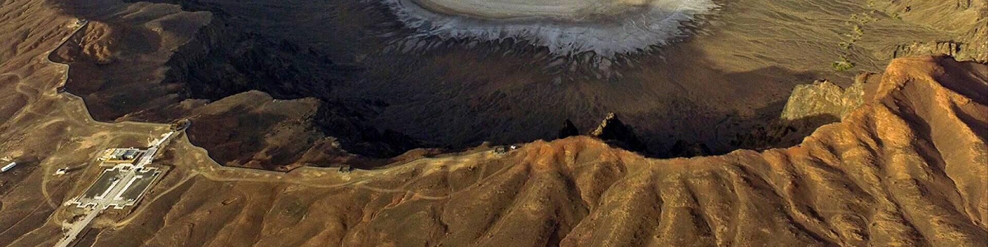 (Al Wahbah crater)
The mouth of the Al-Wa'bah locally called the mud quarry) is located in the desert of the Kingdom of Saudi Arabia, 254 km from Taif and on the western edge of the basalt plateau hills that contain many volcanic cones. This crater is the largest of its kind in the Middle East, with a diameter of 2 km and a depth of 250 meters and has a flat base covered by a thick crust of white sodium phosphate crystal.
It was believed that the crater resulted from the fall of a meteorite, because its outer appearance resembles meteor craters in its circular shape and the height of its sides, but today geologists agree that the crater was formed by volcanic activity that led to an underground explosion that generates steam by the contact of molten rock with groundwater.