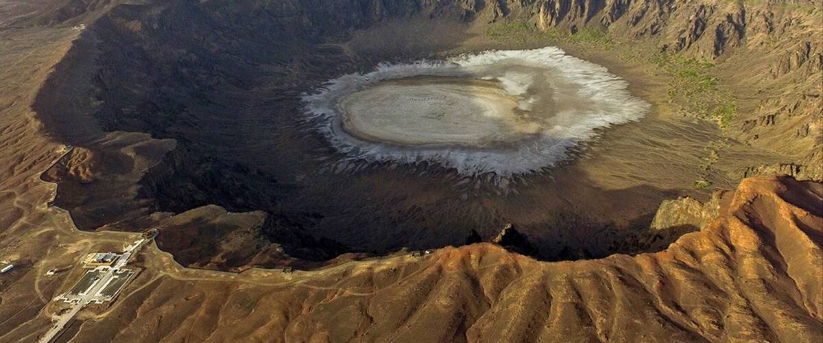 A large crater with a central mound surrounded by a barren landscape.