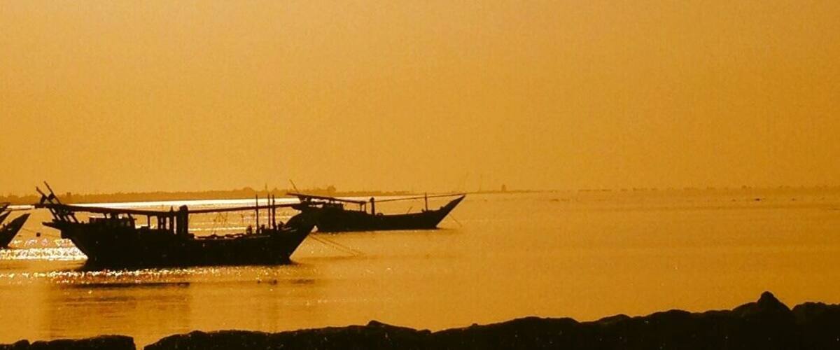 A calm body of water with two boats anchored near the shore.