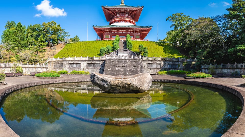 A traditional Japanese pagoda with a stone lantern in the foreground.