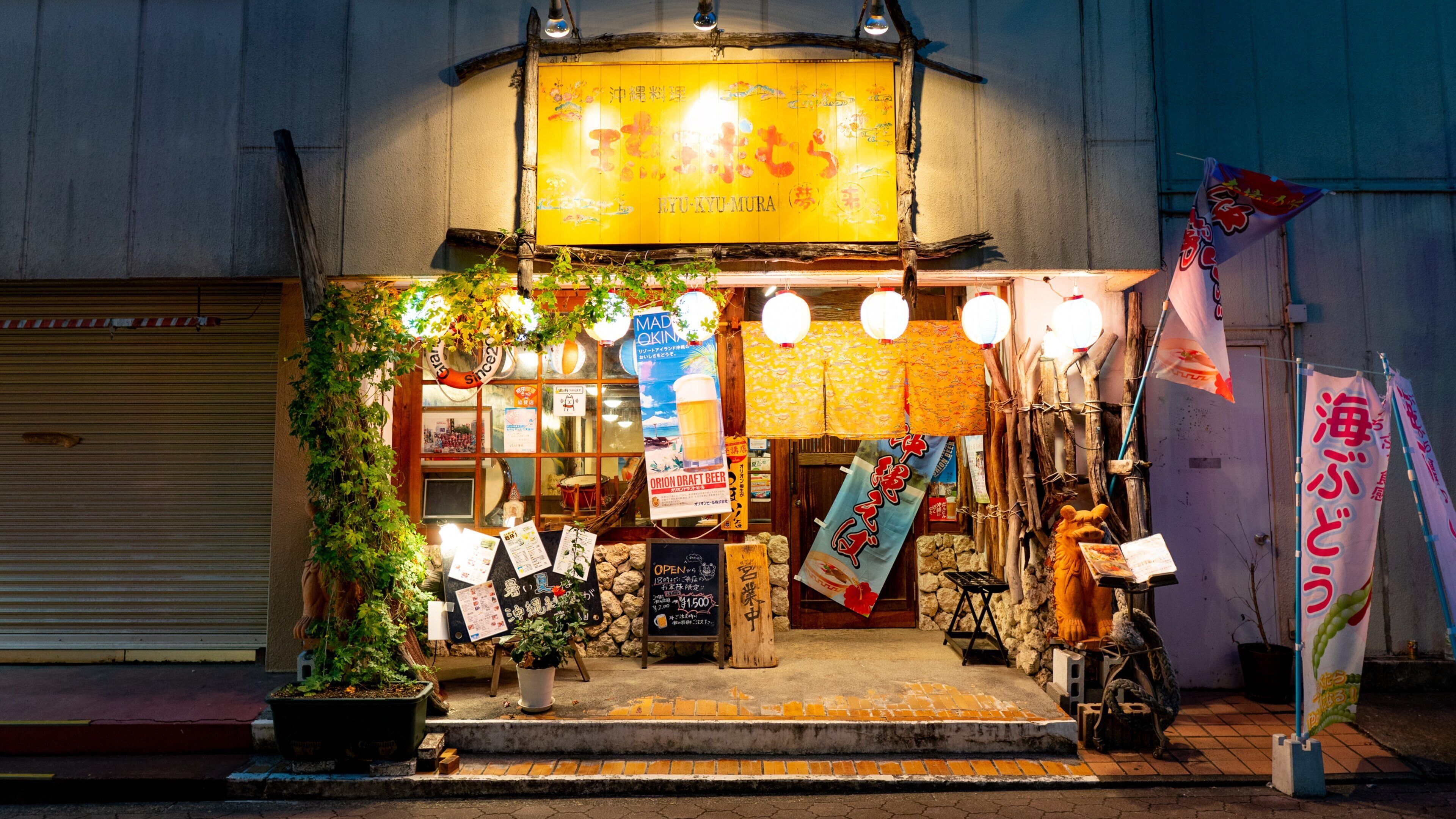 A storefront with a yellow sign, various banners, and a closed shutter door.