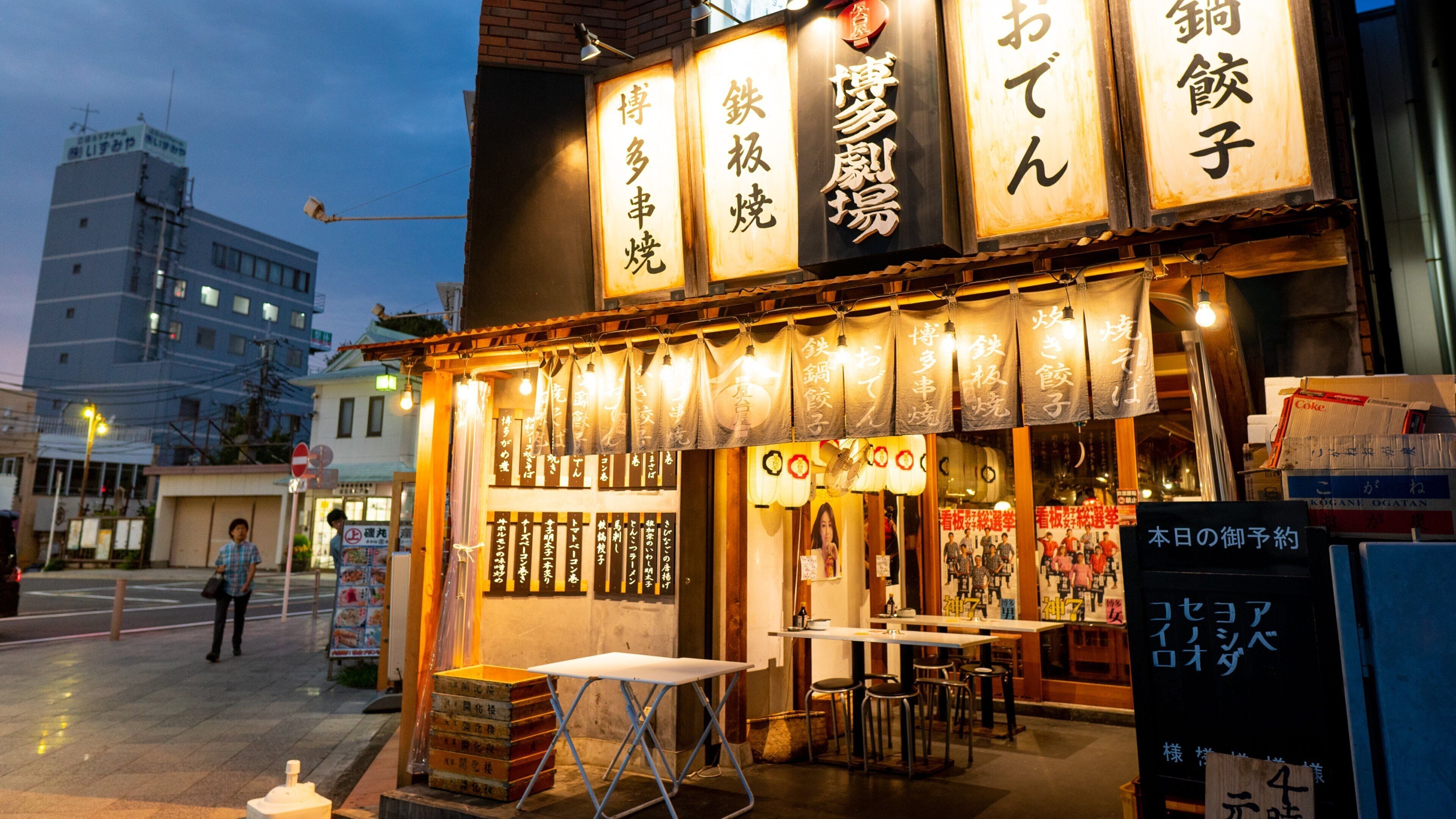 Un ristorante giapponese con insegne illuminate e tavoli all'aperto.