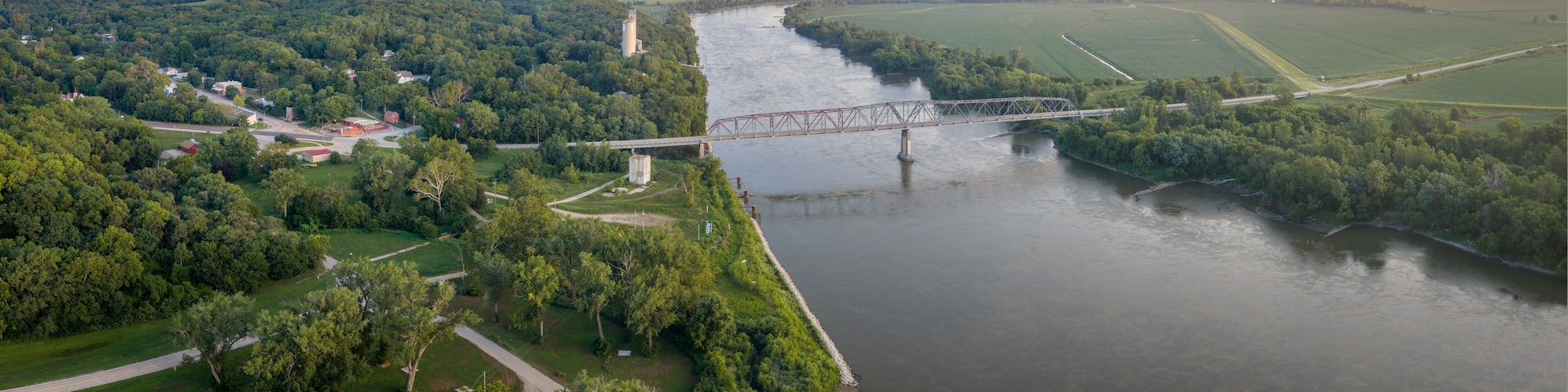 A river with a bridge, surrounded by lush greenery and fields.