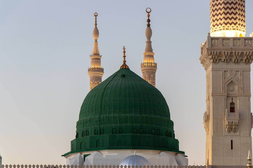 Une mosquée dotée d’un dôme vert et de trois minarets.