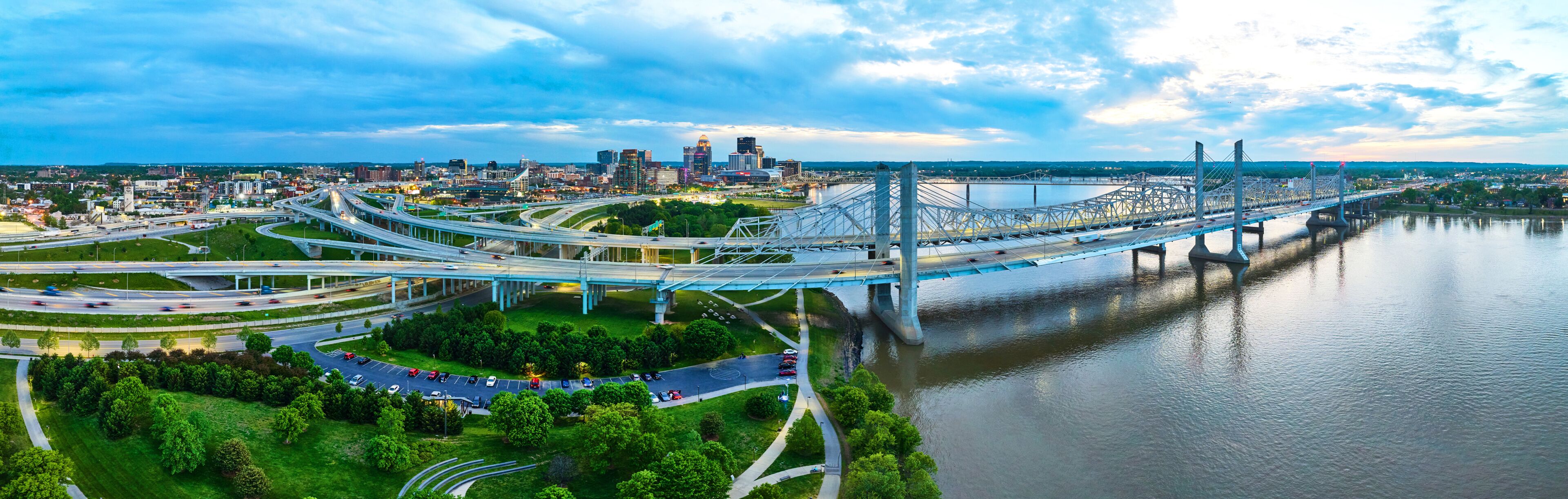 Panorama sunset golden hour suspension bridges outside glowing Louisville city nighttime lights