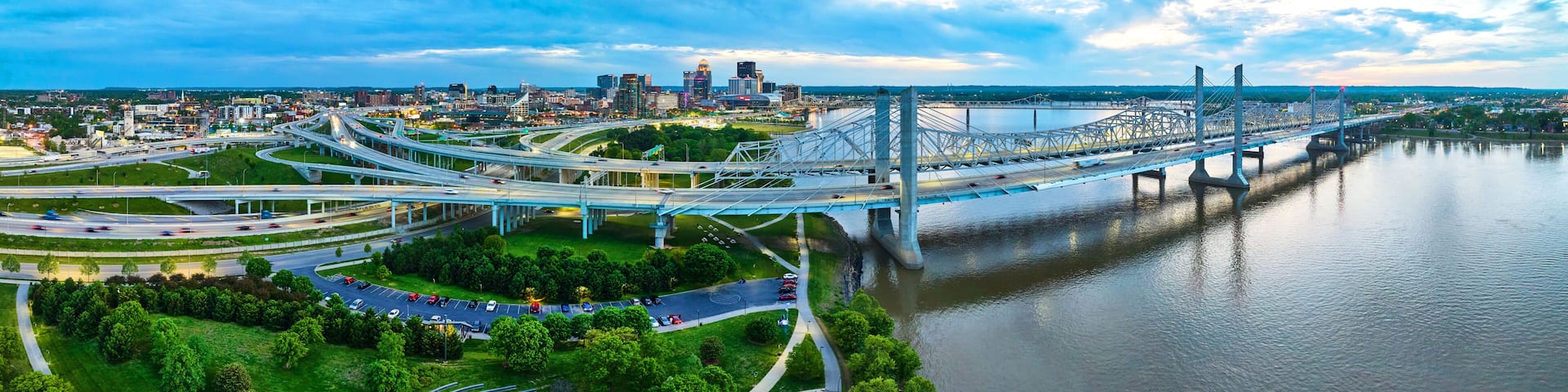 Panorama sunset golden hour suspension bridges outside glowing Louisville city nighttime lights