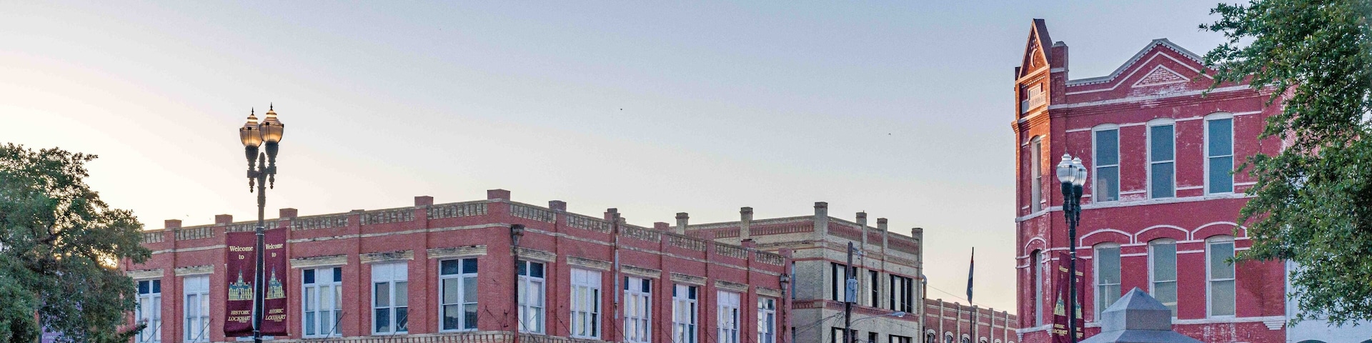 A historic downtown street with red brick buildings, a street lamp, and a small park area.