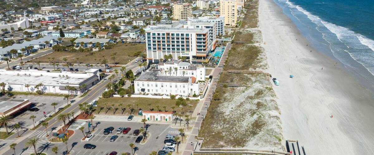 A coastal cityscape with a beach, high-rise buildings, and a parking lot.