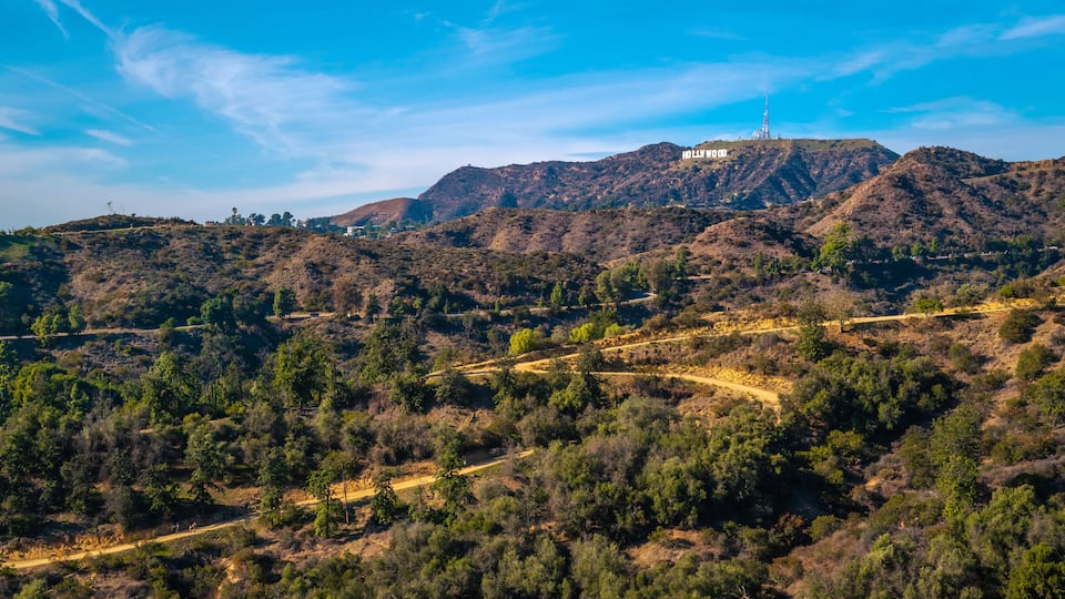 A hilly landscape with the Hollywood sign on a hilltop.