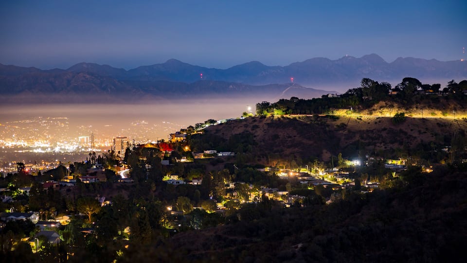 A nighttime cityscape with a mountain range in the background.