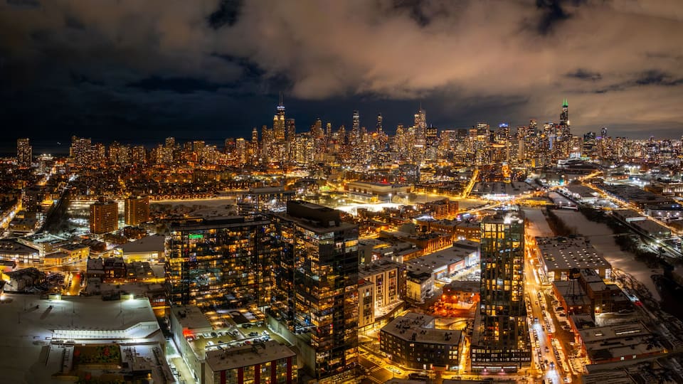 A nighttime cityscape with dense urban architecture and illuminated streets.