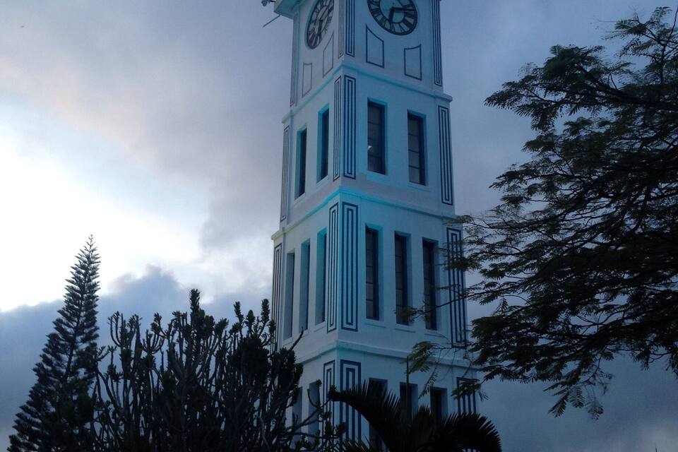 Une tour de l’horloge, surmontée d’un toit en forme de flèche et dotée d’un cadran sur chaque face.
