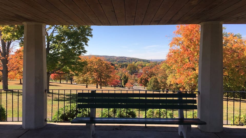 A park pavilion with a bench overlooking a scenic autumn landscape.