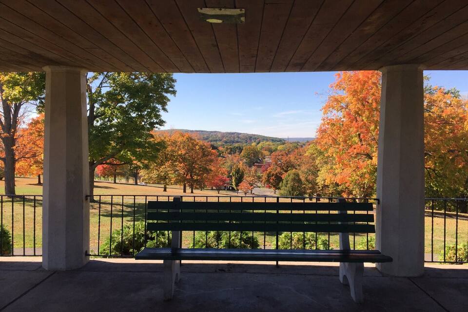 A park pavilion with a bench overlooking a scenic autumn landscape.