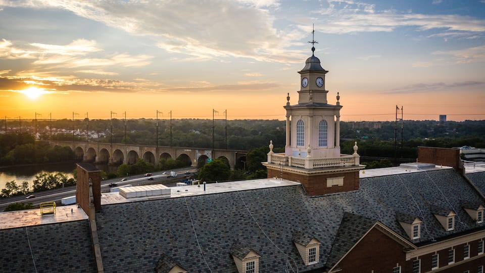 A clock tower, a bridge, and a river at sunset.