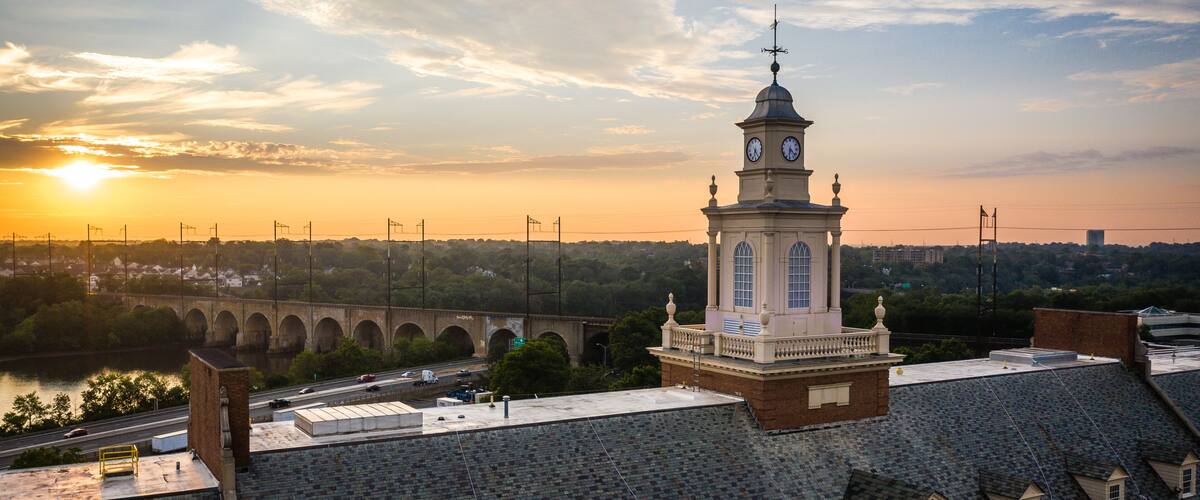 A clock tower, a bridge, and a river at sunset.